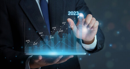 Businessman holding tablet with draws increase arrow graph corporate future growth year 2022 to...