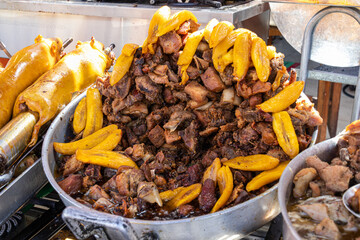Big metal dish with frittata (fried pork) and fried plantains - traditional delicious food of Latin America which serves in local restaurants of typical food. Cuenca, Ecuador