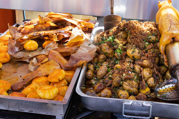 Big metal dishes with potato balls, pig's skin, whole potatoes and roasted guinea pig (cuy) traditional delicious food of Latin America which serves in local restaurant of typical food. Cuenca,Ecuador