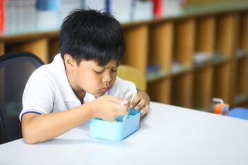 An Asian boy eating breakfast in his classroom. 
