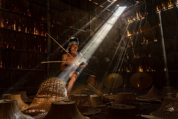 Moment a local northeast Thai male man adult uncle basket weaver maker hand making bamboo basket and hat in a dry grass built room