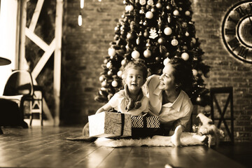 little girl kisses her mother near the Christmas tree. black and white photo