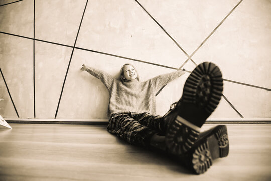stylized photo of a dreaming girl sitting near a wall. black and white photo