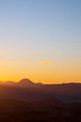 淡いグラデーションの日暮れの空と遠くの山の稜線のシルエット。
