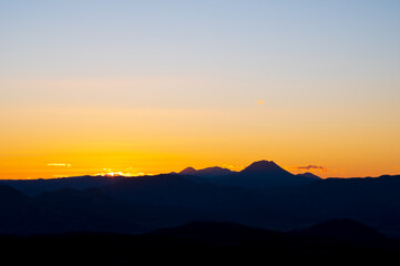 淡いグラデーションの日暮れの空と遠くの山の稜線のシルエット。。