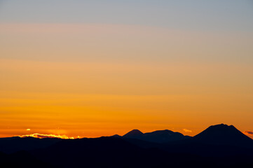 淡いグラデーションの日暮れの空と遠くの山の稜線のシルエット。。
