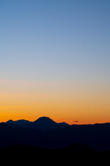 淡いグラデーションの日暮れの空と遠くの山の稜線のシルエット。