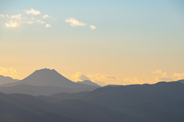 淡いパステルカラーのグラデーションの空を背景にした山並みのシルエット。