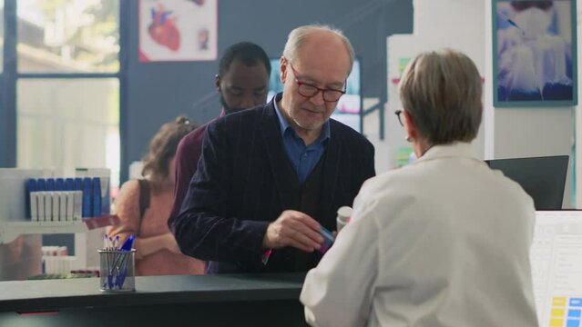 Clients in line wanting to buy medicaments at pharmacy counter, using smartwach, credit card and mobile phone with nfc to pay at pos terminal. Buying pharmaceutical products. Tripod shot.