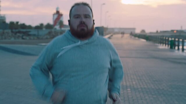 Running, music and fitness with overweight man for losing weight, challenge and cardio endurance. Weight loss, motivation and streaming with plus size runner at beach for health, wellness and stamina