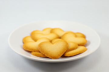 Heart-shaped biscuits on a white plate isolated on white background, selective focus, empty space for text. Valentine's day concept.
