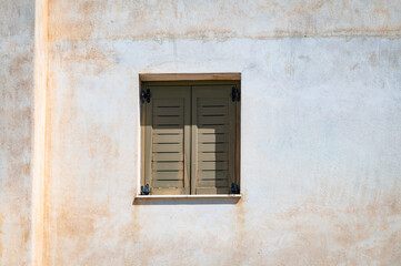 Photo of a shuttered window on the side of a house in a small town on the Greek island or Paros.