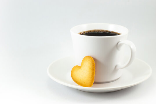 Heart-shaped biscuits and coffee cup with a saucer on a white background, empty space for text. Valentine's day concept.