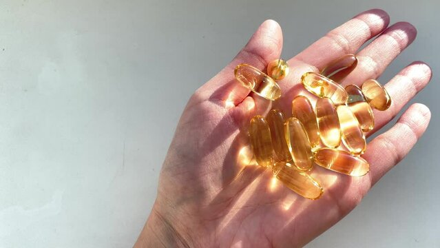 Omega 3 Gold Fish Oil Capsules. Natural Medicine, Sport, Healthy Lifestyle, Supplements, Dietary, Nutrition, Weight Loss, vitamin D. Pouring Fish Oil Capsules to Hand, Close up. Omega3 closeup in the 