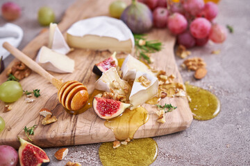 Sliced Camembert or brie cheese on wooden cutting board at domestic kitchen