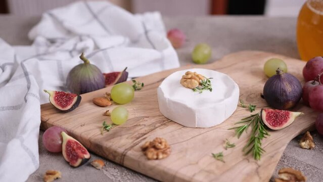 Camembert or brie cheese on wooden cutting board at domestic kitchen