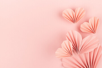 Elegant soft pink paper ribbed hearts in oriental origami style as soar flow on pink background,...