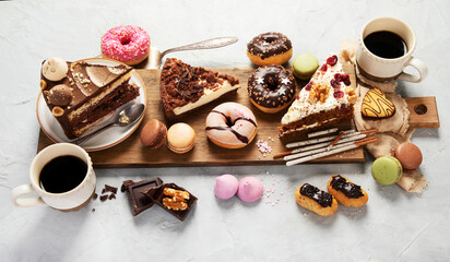 Table with various cakes, cookies, donuts and coffe cups on light background.