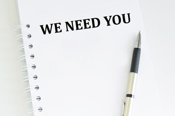 We Need You inscription on a notebook on a table with a pen, a business concept