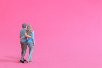 Miniature people man and woman in casual cloth standing together isolated on pink background , Valentine's day concept