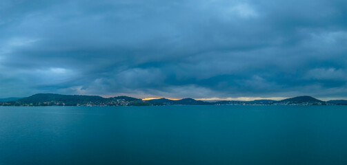 Fototapeta na wymiar Sunrise waterscape panorama with rain clouds moving in
