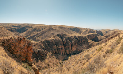 Fototapeta na wymiar Atemberaubender Panoramablick auf dem Olive Trail - Familie blickt von einem Aussichtspunkt aus in eine enge felsige Schlucht mit Felswänden aus Sedimentgestein, Naukluft Gebirge, Namibia