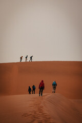 Touristen wandern über einen Grat in Richtung des nebelverhangenen Gipfels der Düne Big Daddy im Sossusvlei (Namibia)