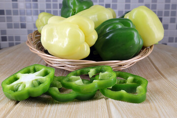 whole sweet bell pepper on a wicker plate and cut pieces on the table
