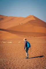 Frau blickt in Richtung der Düne Big Daddy, über deren Grat Touristen auf den Gipfel wandern (Sossusvlei, Namibia