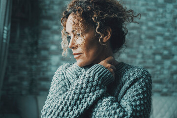 Emotional feeling portrait of woman hugging herself with love and protection concept. Serene and intimate adult female people embracing her body and neck looking on her side outside the window