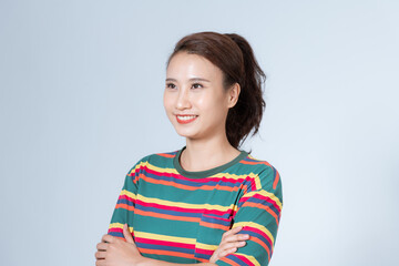 Fototapeta premium Beautiful girl with folded arms looking at camera against grey wall