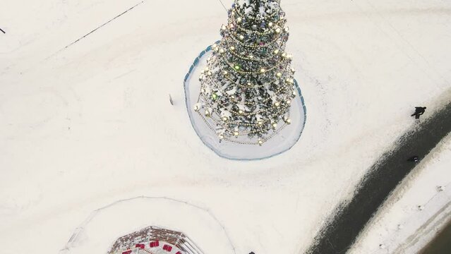Beautiful Christmas tree with garlands in the city square, aerial view. New Year's, green spruce fabulously decorated and covered with snow. City of Vladimir, Cathedral Square, Russia. UHD 4K.
