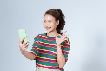 Portrait of asian woman showing OK sign and using mobile phone, recommend application, standing over white background
