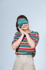 Happy young woman in sleepwear dreamily smiling and sleeping in morning against white background