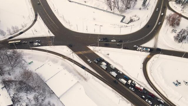 Top view of the city road with cars, snow lies. Vehicles drive and stand at a traffic light. Regulated intersection, interchange. City of Vladimiro, Lybidskaya highway. UHD 4K.