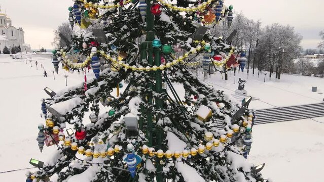Golden and sparkling garlands on a Christmas tree, aerial view. New Year's, green spruce fabulously decorated and covered with snow. City of Vladimir, Cathedral Square, Russia. UHD 4K.