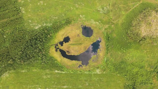 Aerial view of a fabulous lake that seems to be laughing cunningly. A pond with big eyes. The beauty of nature. A joyful expression on a natural lake. Happy nature smiles. 4K UHD.