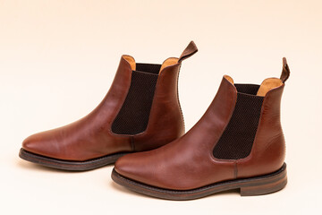 Footwear ideas. Closeup of Pair of Classic Leather Chealsea Boots As Still Life Concepts Placed Close to One Another Over Beige Background