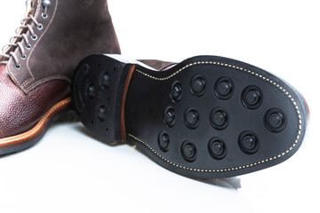 Footwear Ideas. Premium Dark Brown Grain Brogue Derby Boots Made of Calf Leather with Rubber Sole Placed Reversed With Sole Exposed Over White