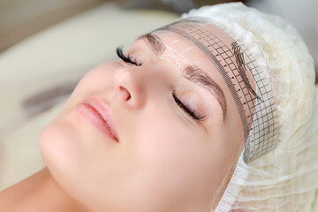 Closeup of Facial Tattoo Markup with Transparent Facial Ruler On Eyebrows of Young Caucasian Woman During a Process of Permanent make up in Salon.