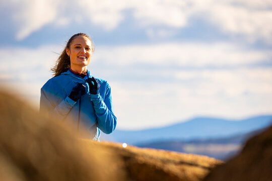 A woman in a blue jacket smiling in the mountains
