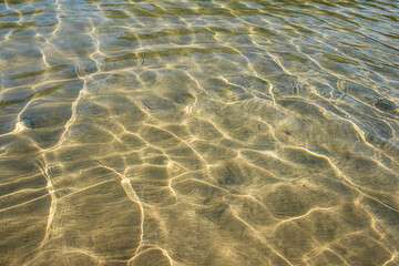 Fototapeta na wymiar A clear water surface on a sunny day. Crystal clear water texture. Light diffraction