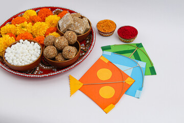 Happy Makar Sankranti, Pongal and Uttarayan with Kite, haldi kum kum bowls and tilgul sweets