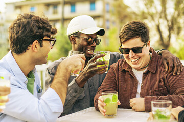 Diverse group of 20s young friends joking and laughing at the outdoor pub cafe