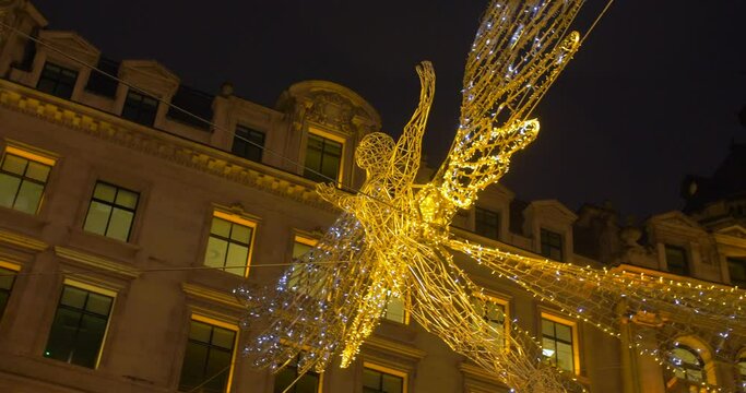 Low angle shot of beautiful Christmas street decorations of flying angel near Piccadilly Circus, London, UK at night time. 4K.
