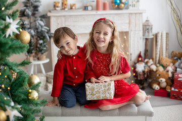 Happy cute children, siblings on Christmas, enjoying holiday, opening presents and eating cookie