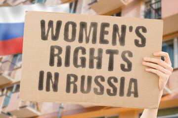 The phrase " Women's rights in Russia " is on a banner in men's hands with blurred background. Cheering. Community. Confidence. Courage. Crowd. Defend. Determination. Different. Diversity. Fight