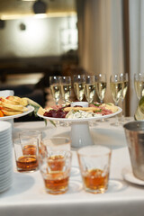 A tray with fruit, champagne, whiskey is on the table with a white tablecloth.