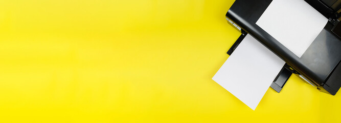 Top view of the printer and a blank sheet of a4 paper on a yellow background.Banner.Photo printing on a photo printer.