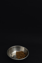 Dry dog food in an aluminum plate on a black background, dog food